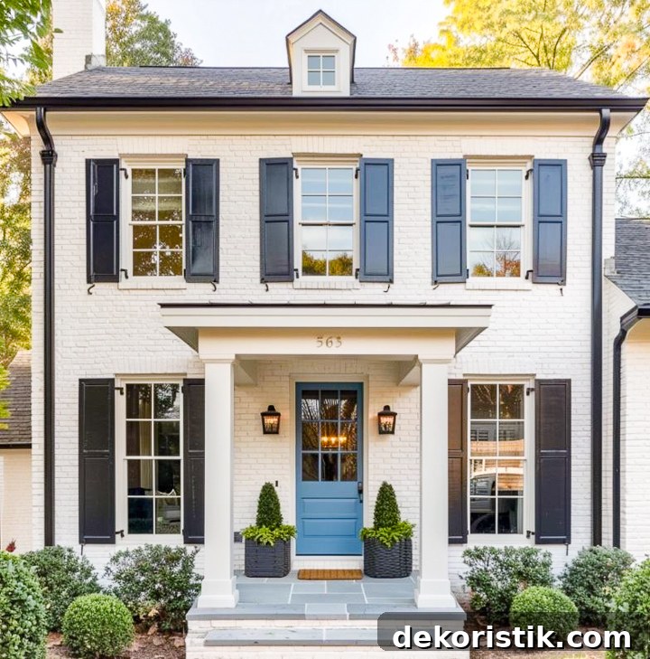 small front porch on a white house with greenery and flowers and a blue door