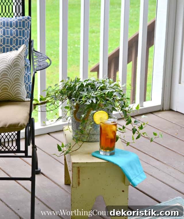 A small stool is beside the chairs on the porch.