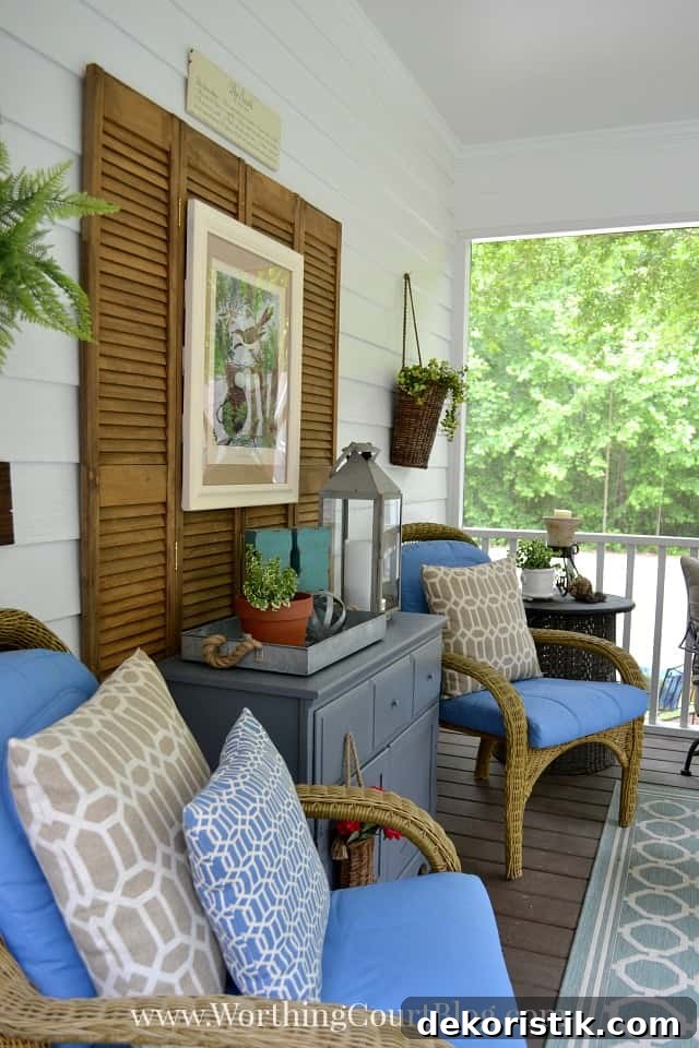 The screened in porch decorated with chairs and blue pillows and artwork.