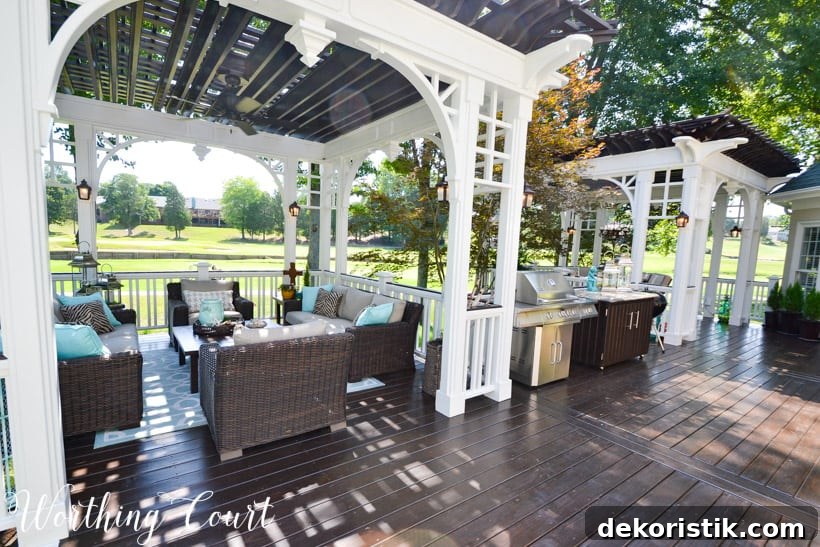 A large deck with beige furniture and a bbq in the middle.