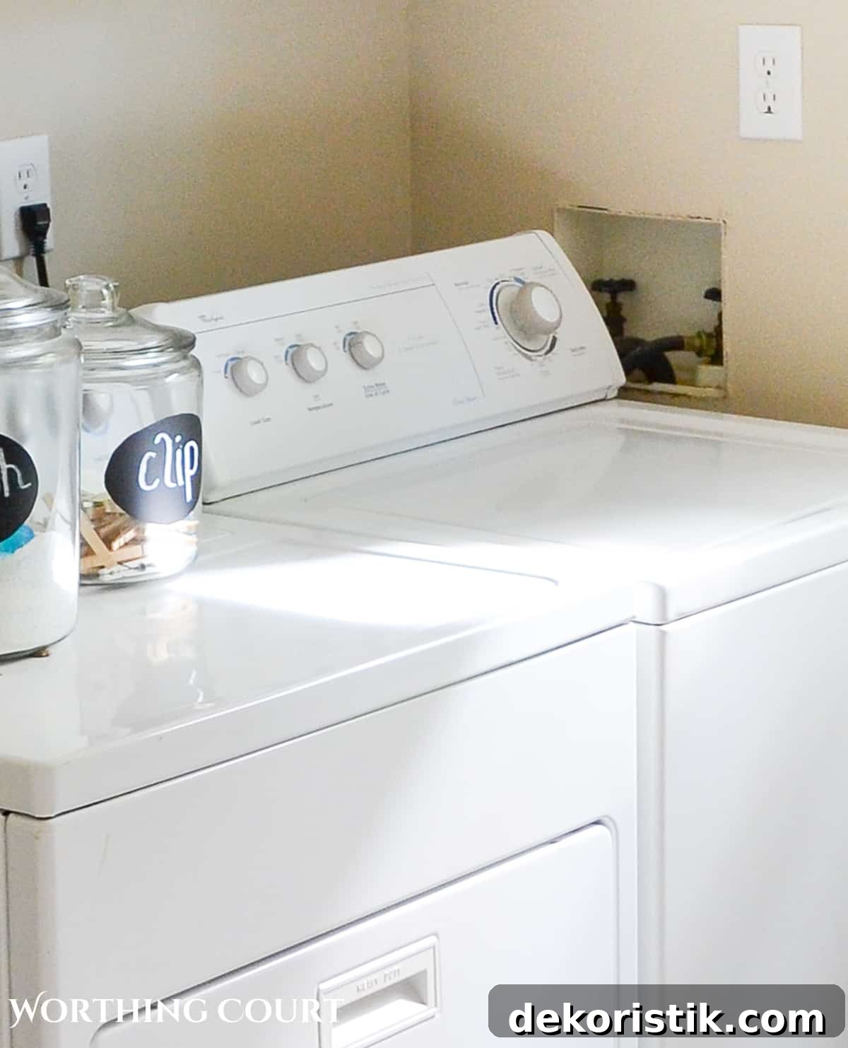 white washing machine beside hole in the wall for the washer hookups