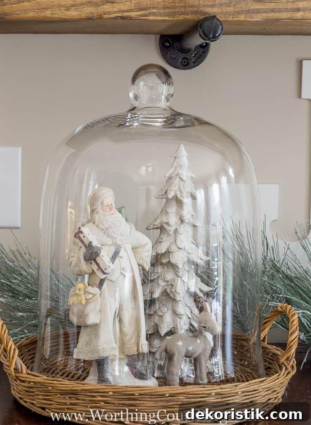 A glass cloche with a small deer and Santa and Christmas tree.