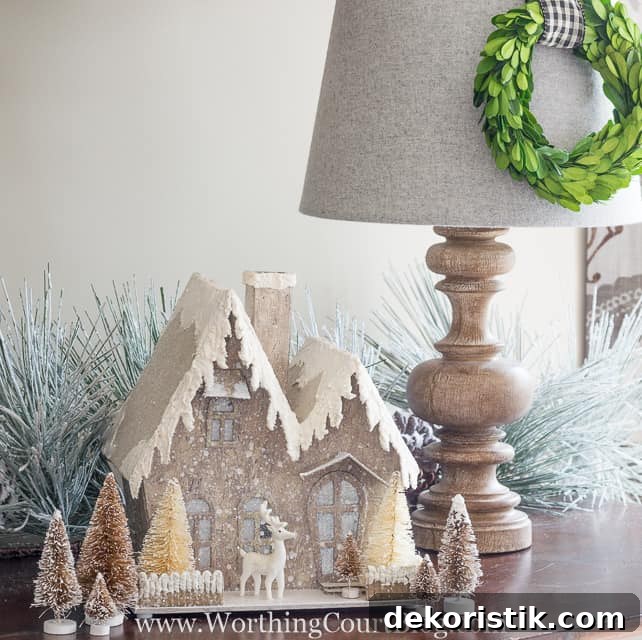 A glittery Christmas house is on the sideboard.