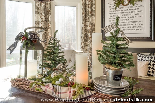 A centerpiece for the table with a mini tree, ribbons, candles and bells.