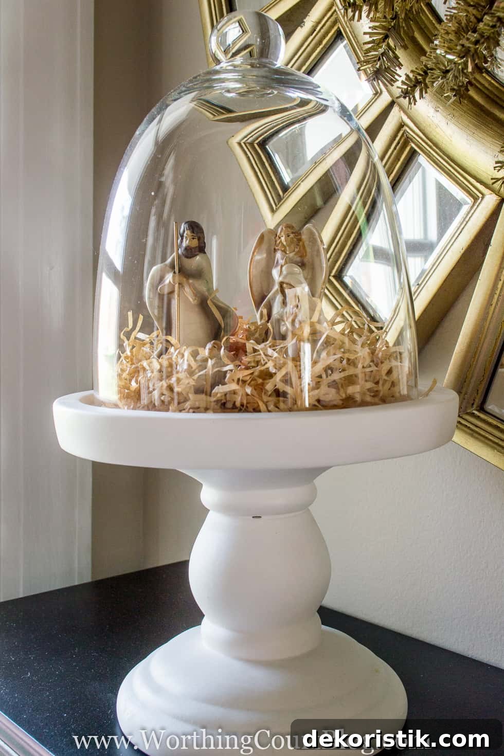 A tiny nativity set is very simply displayed under a glass cloche.