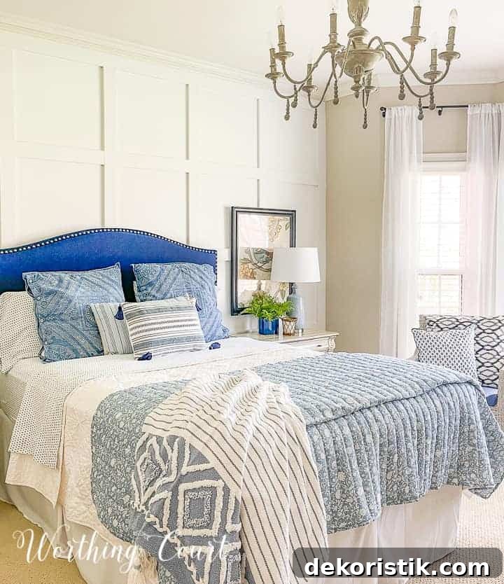 bed with a blue upholstered headboard and blue and white bedding against a white board and batten wall