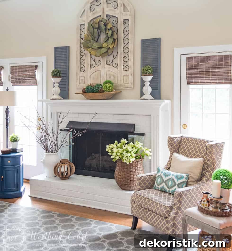 Spring fireplace mantel with tulips, magnolia wreath, pussy willow branches and boxwood orbs arranged across the mantel and hearth