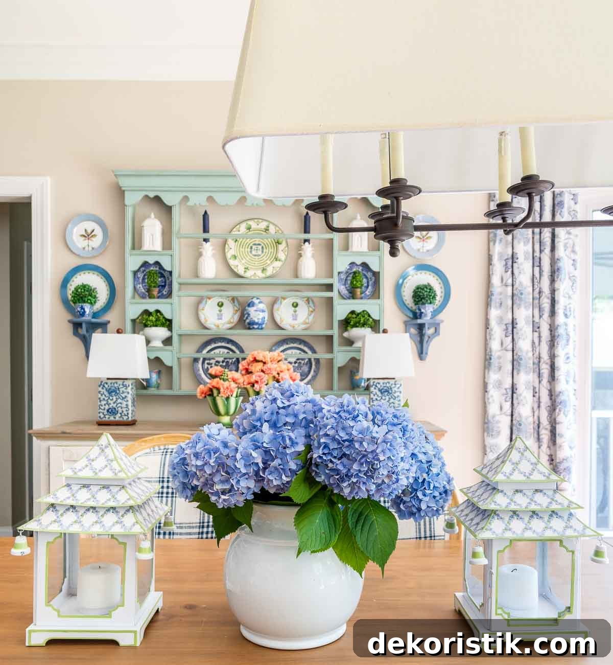 centerpiece on a table with blue hydrangeas and white and blue pagoda shaped lanterns with a plate rack in the background