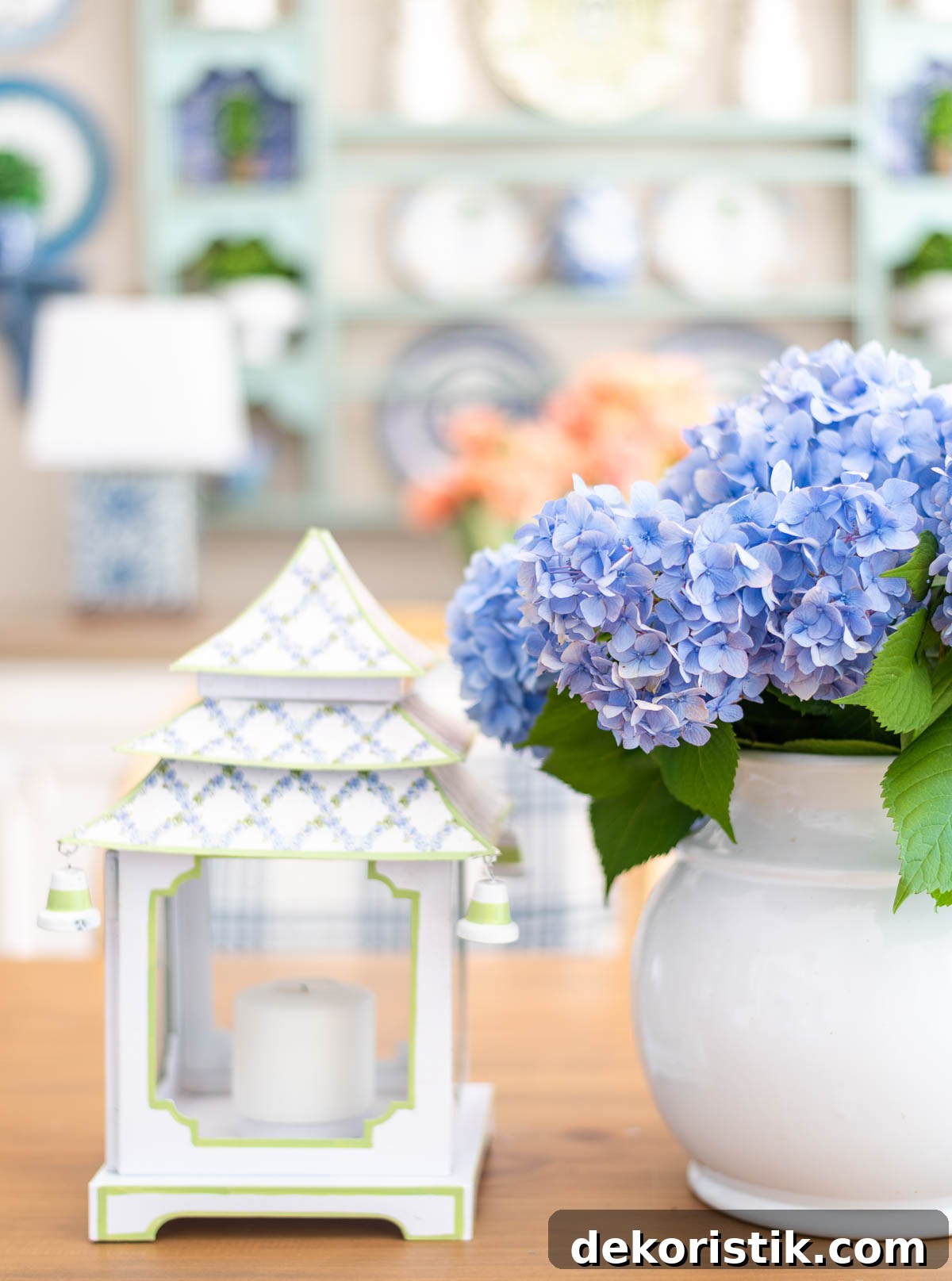 centerpiece on a table with blue hydrangeas and white and blue pagoda shaped lanterns with a plate rack in the background