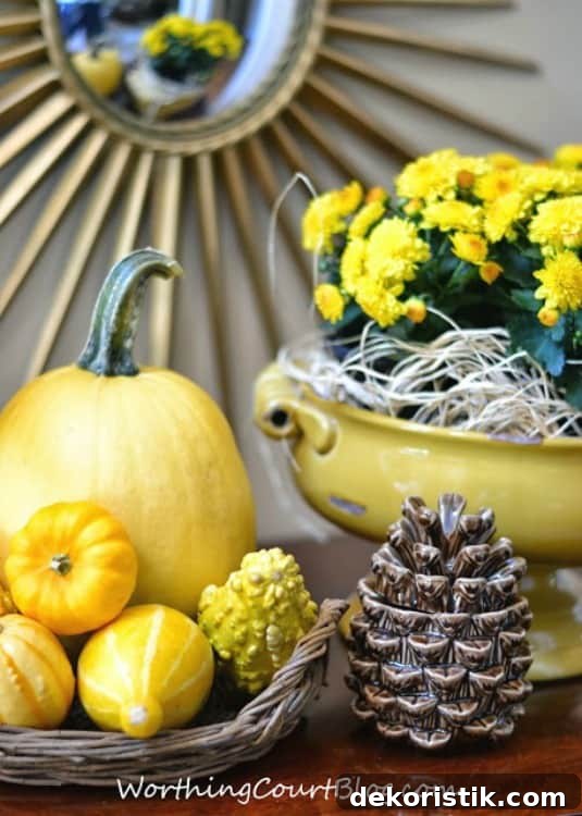 A fall vignette with pumpkins and gourds beside a yellow dish filled with yellow flowers.