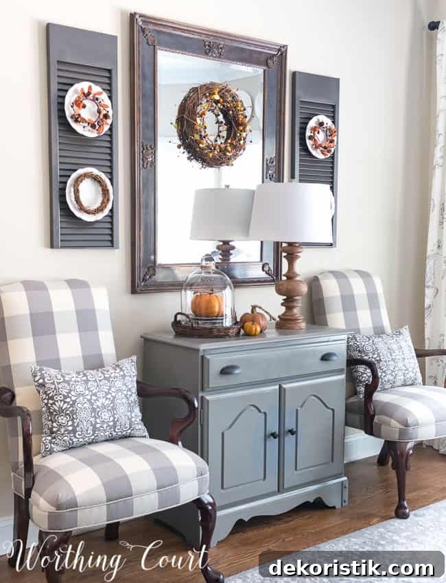 Fall dining room cabinet vignette with a glass cloche and a pumpkin inside the cloche.