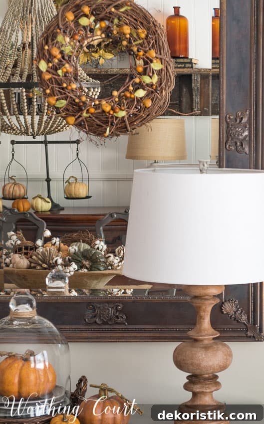 Fall decor reflected in a mirror with a grapevine wreath on it.