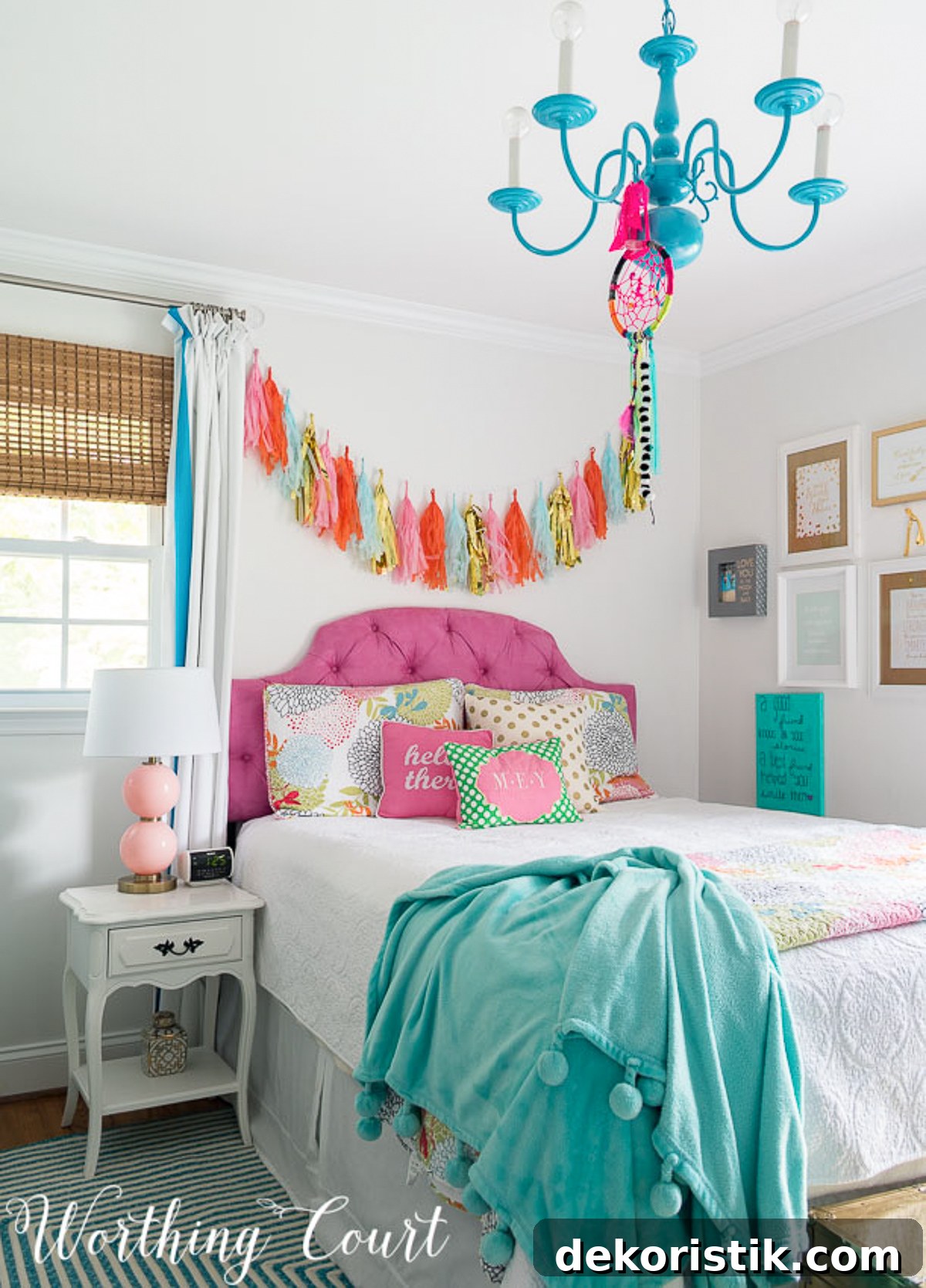 colorful teenage girl's bedroom with a pink headboard, white painted furniture, teal lampshades, teal throw, brass trunk, tissue paper garland and a gallery wall