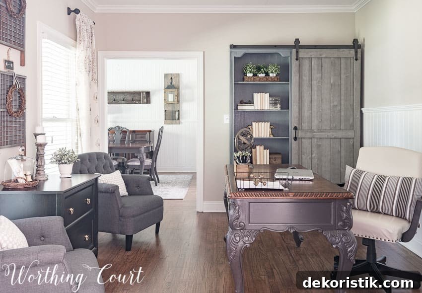 A home office with a grey desk and fabric chair, and a farmhouse style bookcase.
