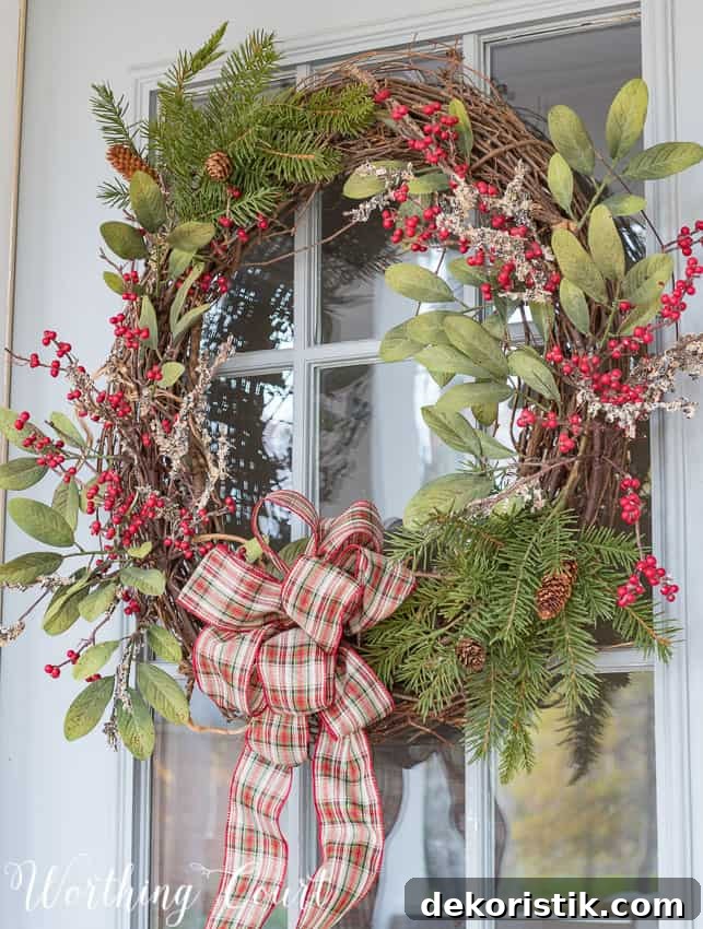 DIY grapevine Christmas wreath with red berries and a plaid bow.