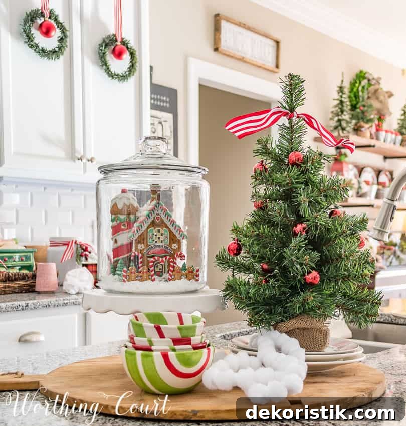 Kitchen island Christmas vignette with a gingerbread house in a small glass canister.