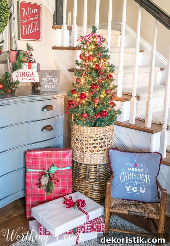 Small Christmas tree for a foyer with presents underneath it.