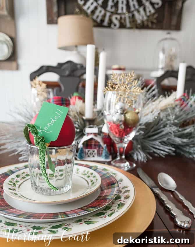 Christmas dinner place setting with gold charger, gold rimmed holly dishes and tartan plaid dishes. 