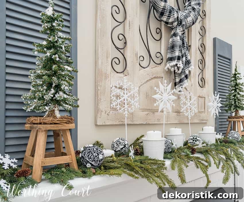 Winter mantel decorated with faux greenery, white candles and diy snowflakes on a stick.