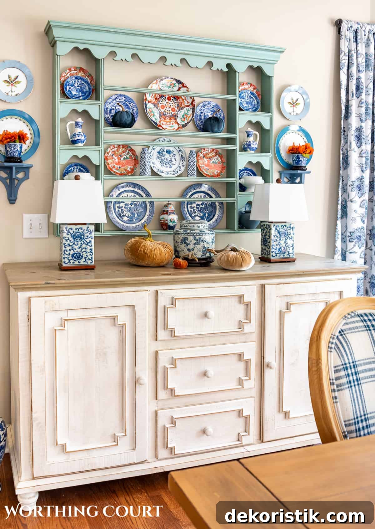 plate rack above a white sideboard filled with blue and white dishes and orange dishes for fall