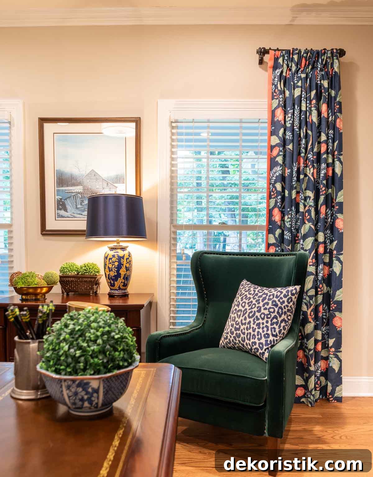 green velvet chair positioned in front of window with navy blue floral draperies