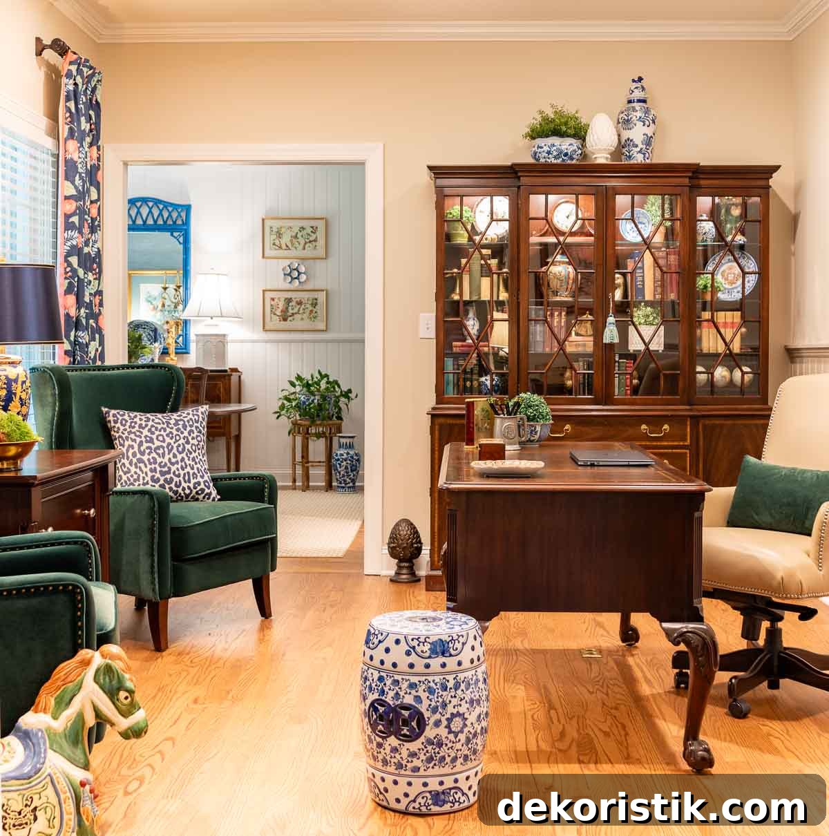 home office with traditional wood furniture, green velvet arm chairs, navy blue floral curtains and colorful accessories