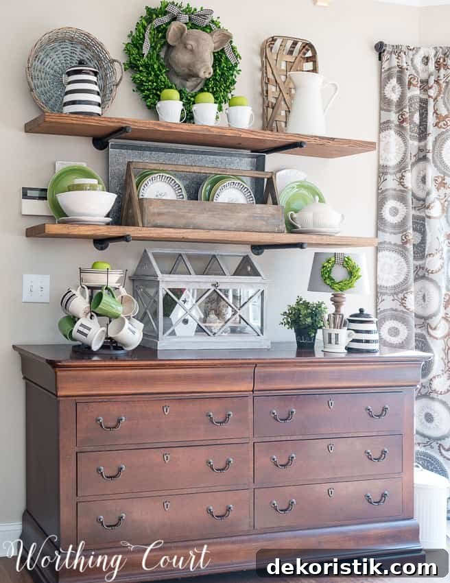 Wooden shelves with tea cups, a wreath, and a geranium all with pops of green.