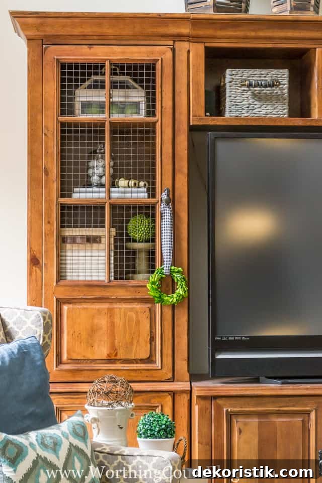 The before and after of this family room is amazing. It was taken from dark and dated to light and bright filled with rustic farmhouse touches, which includes a rustic entertainment center where the glass in the doors was replaced with cage wire.