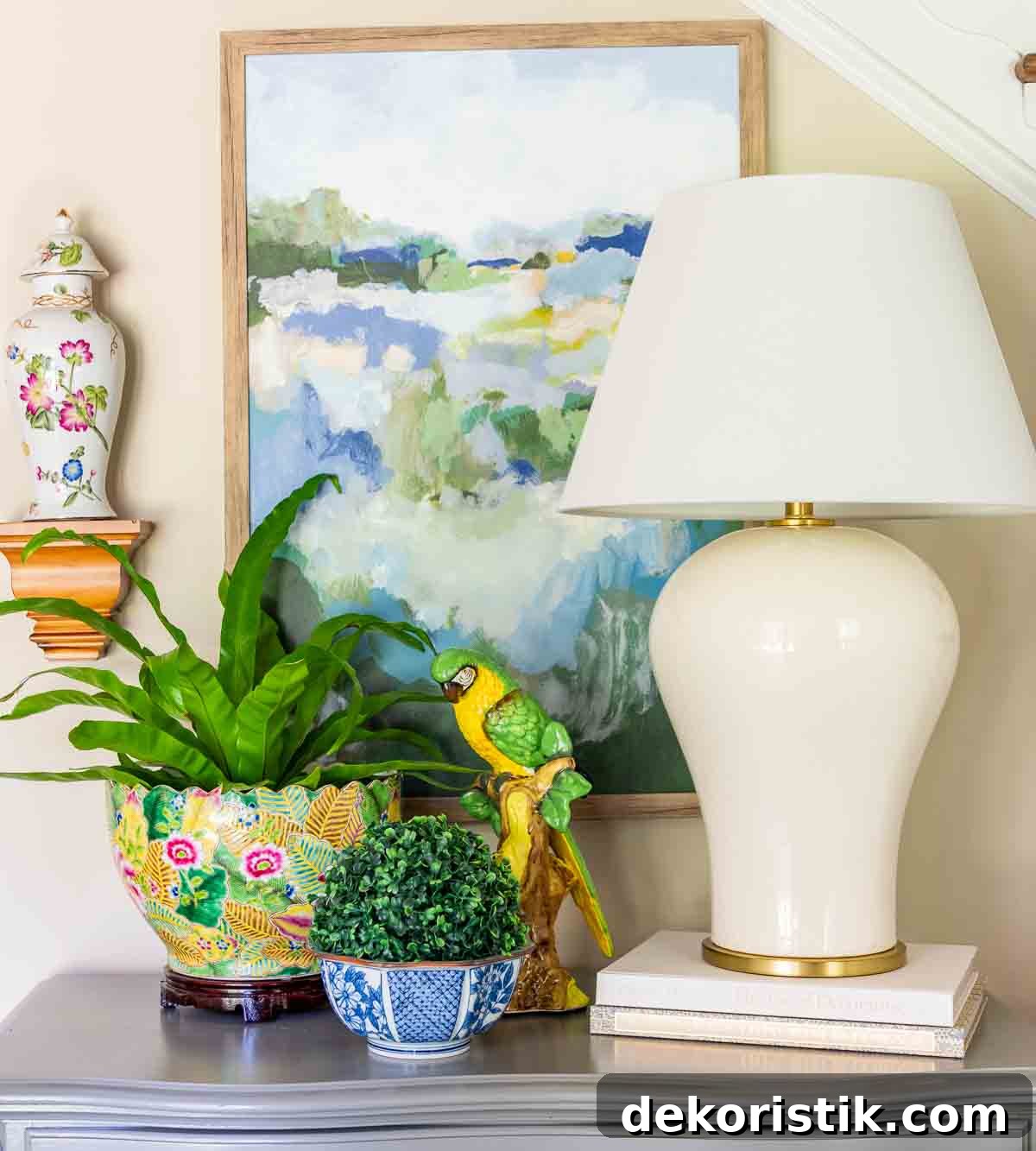 off white lamp and colorful accessories on top of a small gray chest