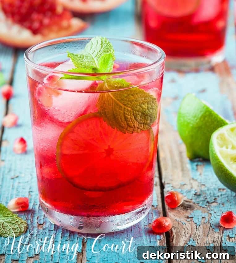 Glass filled with ice and pink lemonade on a wooden table.
