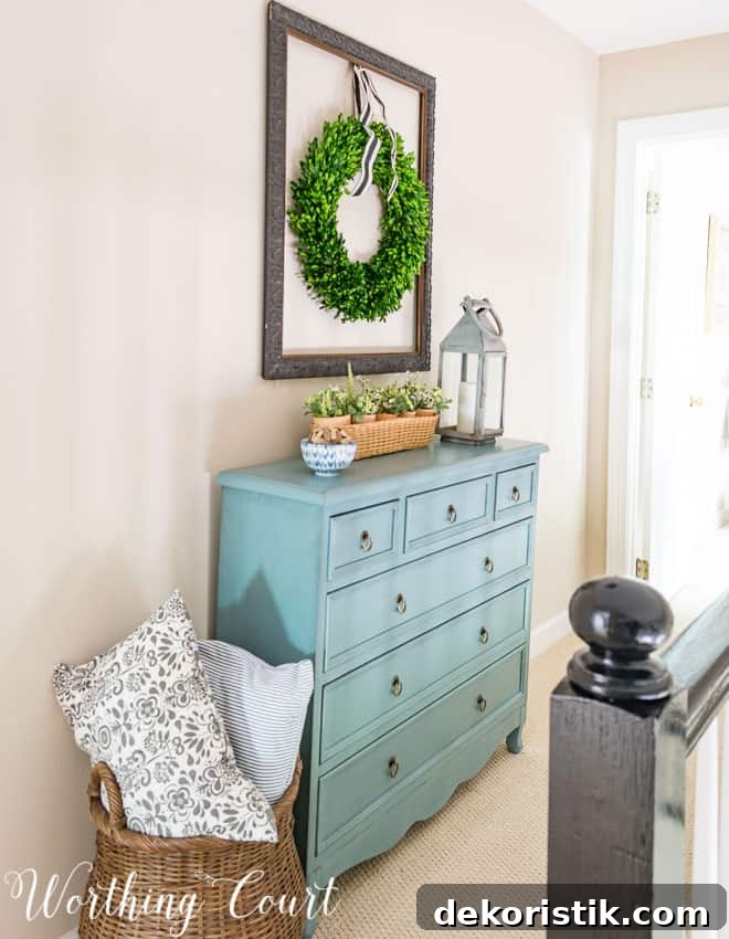 There is a turqoise chest of drawers against the wall in the hallway.