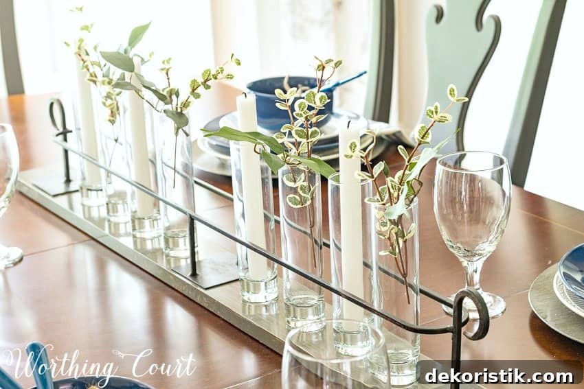 Simple summer centerpiece with cylindrical glass and greenery.
