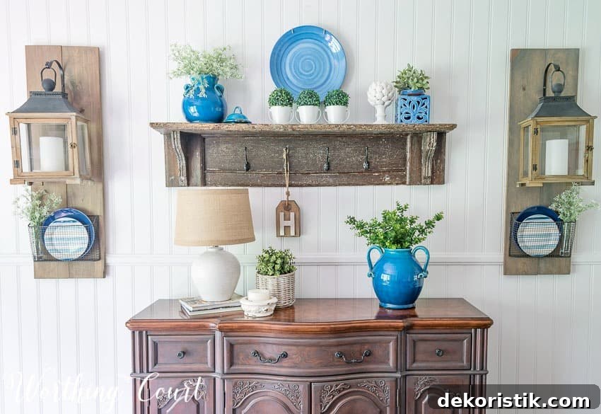 Summer sideboard decor with a lamp, blue vase and a vintage wooden shelf.