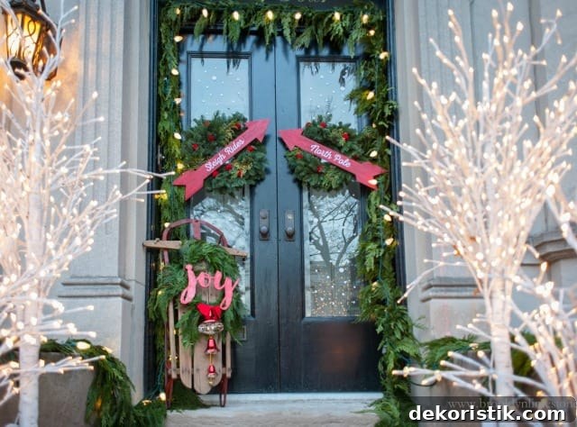 A garland of fresh greenery is around the front door with a sign that says joy.
