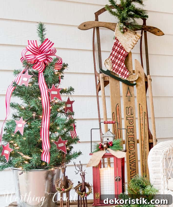 A small Christmas tree is in a galvanized bucket on the front stoop.