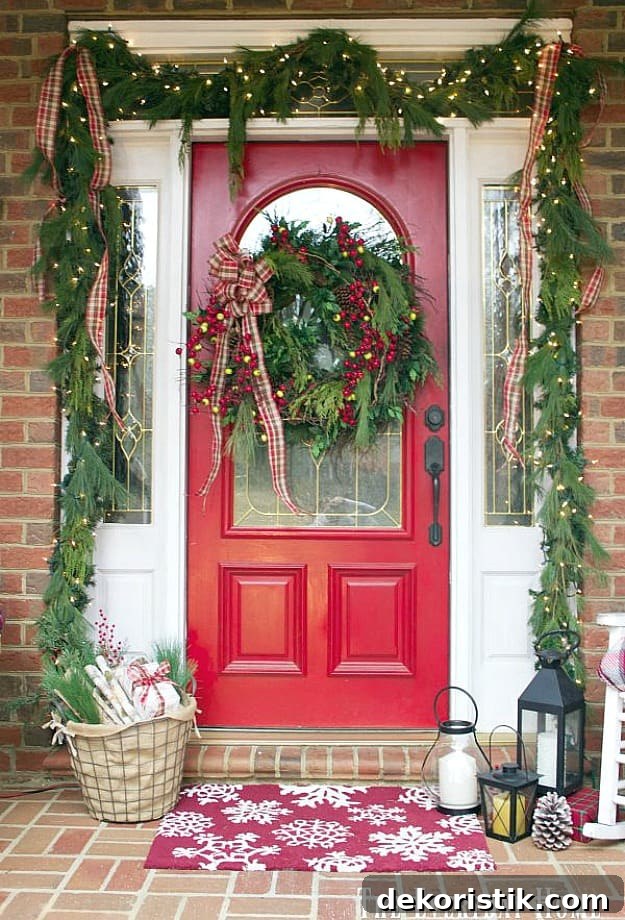 A red door with holly and a large wreath on it.