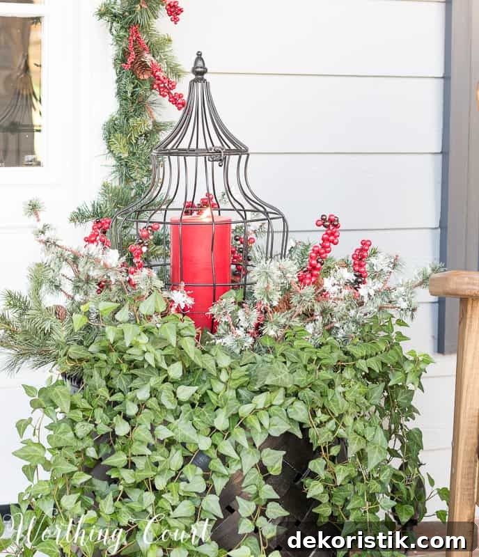 Christmas outdoor container filled with ivy, faux greenery and a lantern #christmas #christmascontainer #christmasurn