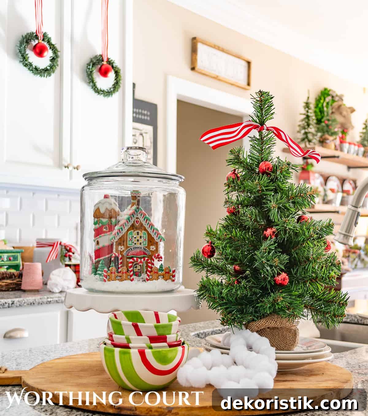 Christmas vignette on a kitchen island with a small tree and ceramic Christmas house.