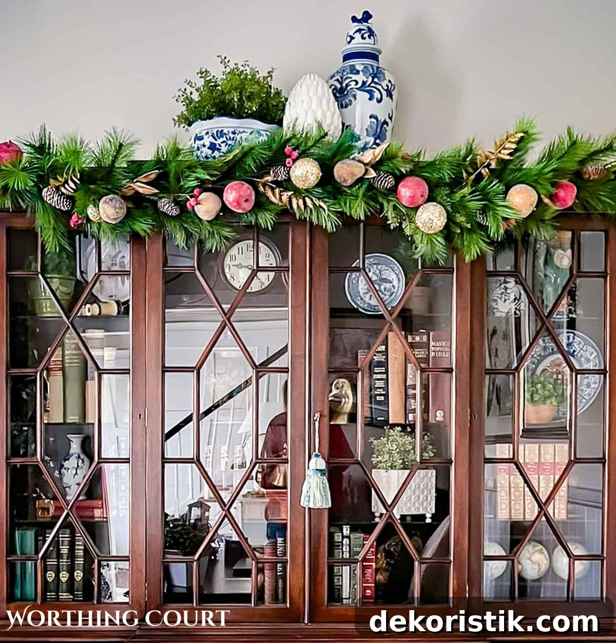 wood china cabinet with glass doors with a Christmas garland across the top
