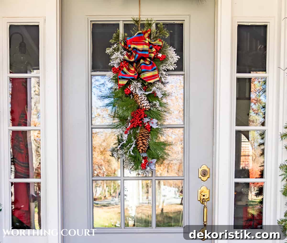Christmas swag hanging on a gray front door with glass panes