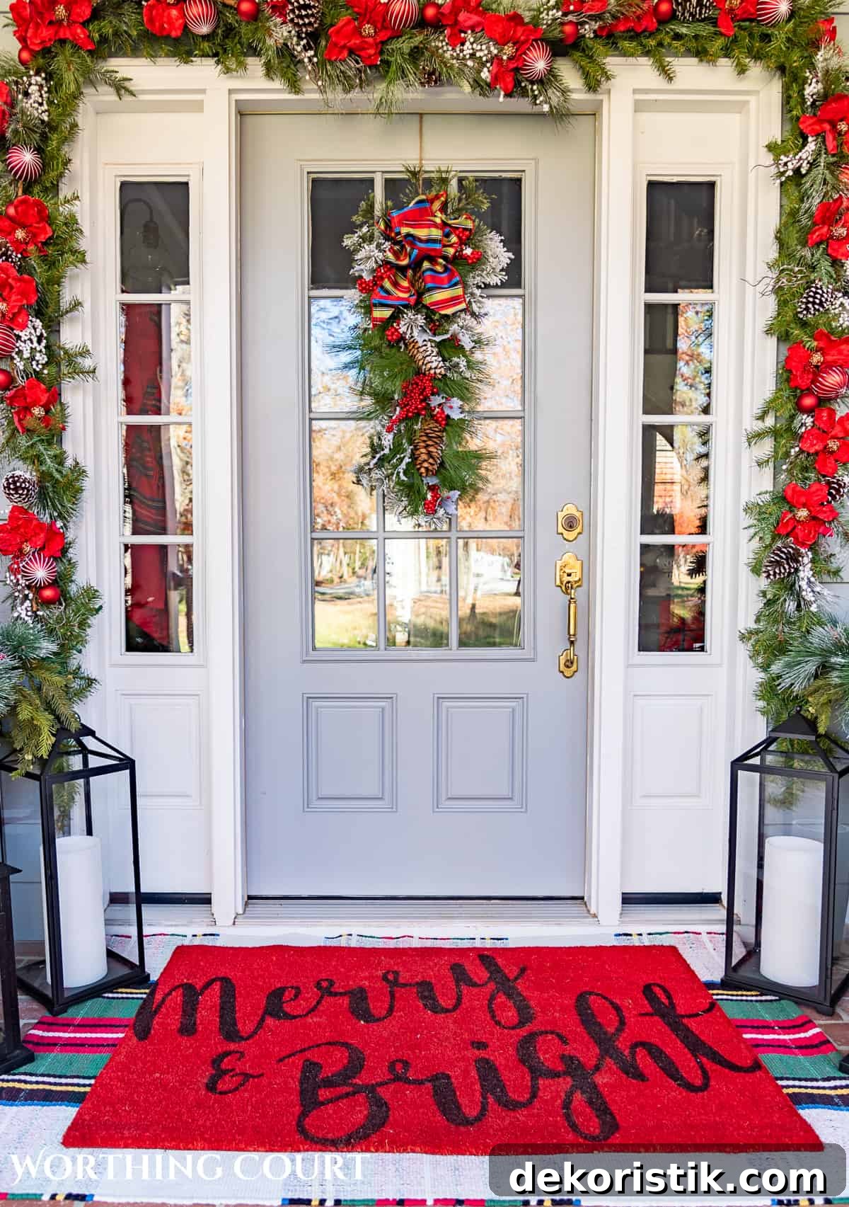 gray front door with glass panes and white sidelights surrounded by a Christmas garland