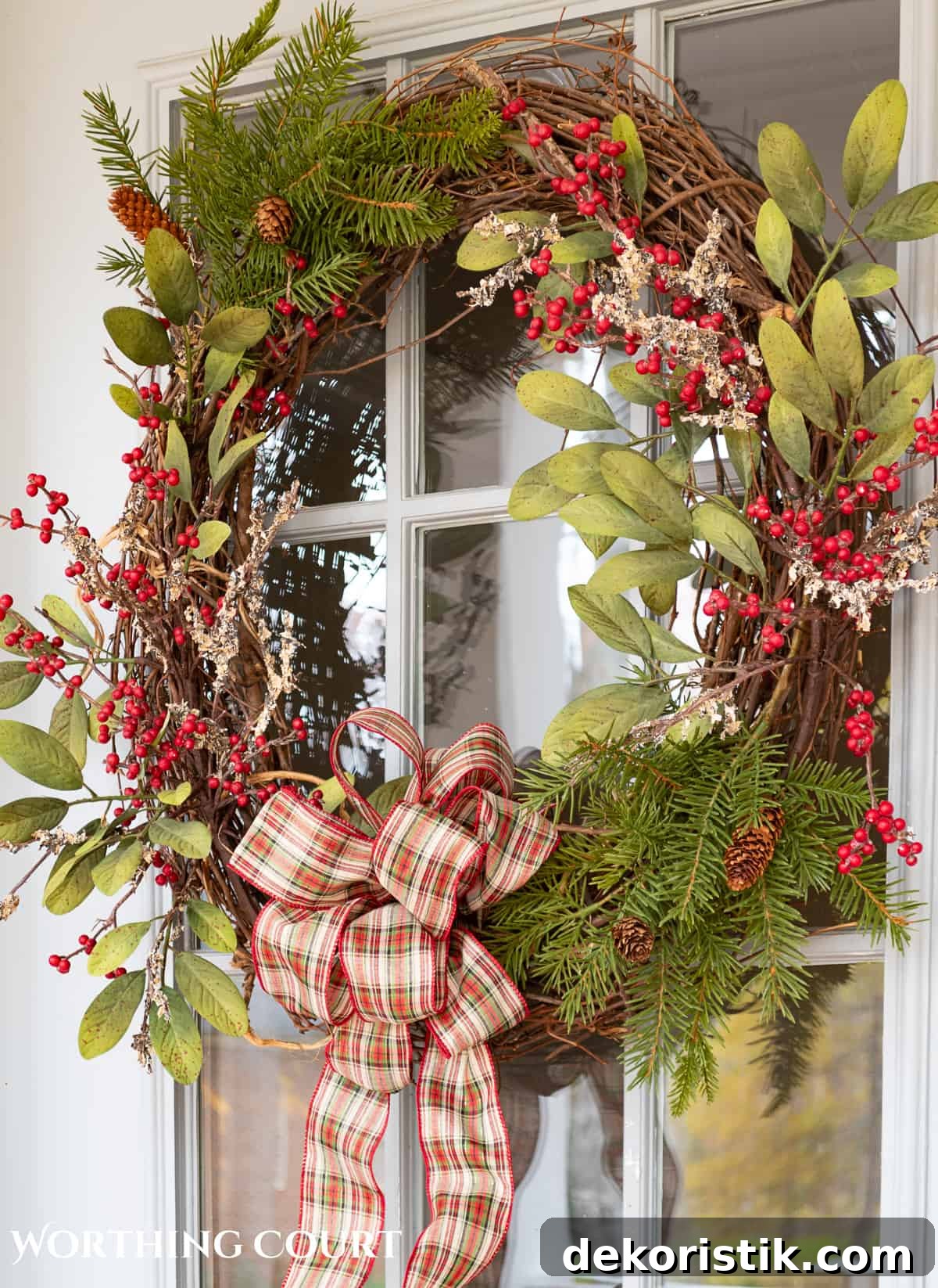 Christmas wreath with natural elements hanging on a front door with glass panes