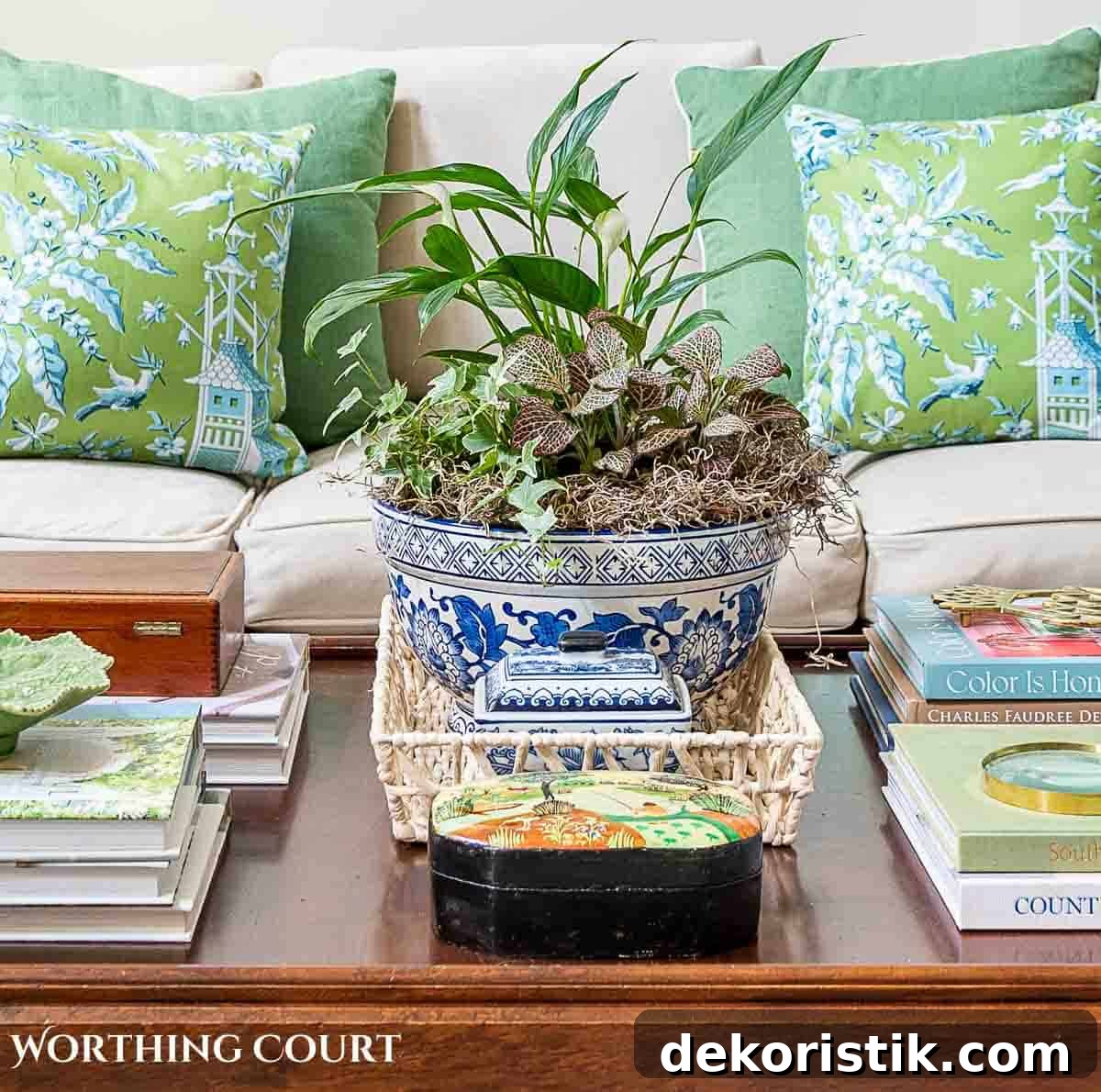 Spring Home Decor Ideas to Refresh Your Space 11 plants in a blue and white bowl on a coffee table decorated for summer with green pillows on sofa in background