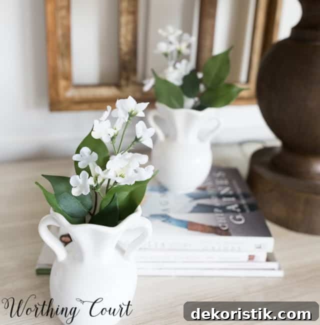 white home decor accessories filled with faux white flowers on a nightstand