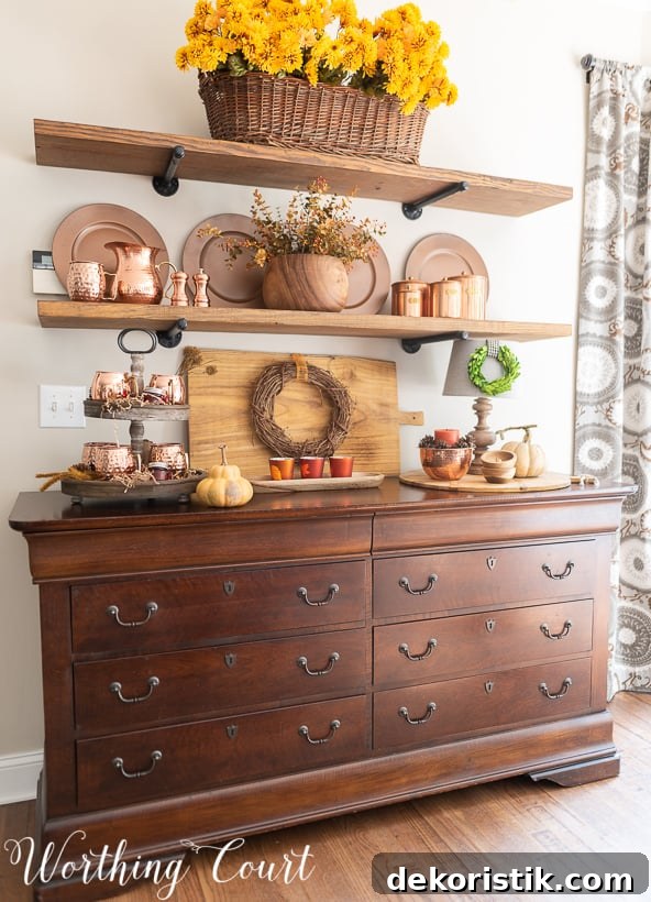 A wooden hutch with open shelves above it and copper accents on the shelves.   The top shelf has a a basket full of golden yellow flowers.