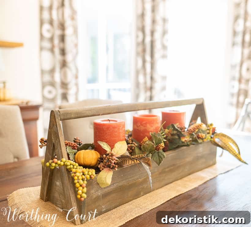 There is a vintage wooden toolbox filled with candles, mini pumpkins, and leaves on the table as a centerpiece.