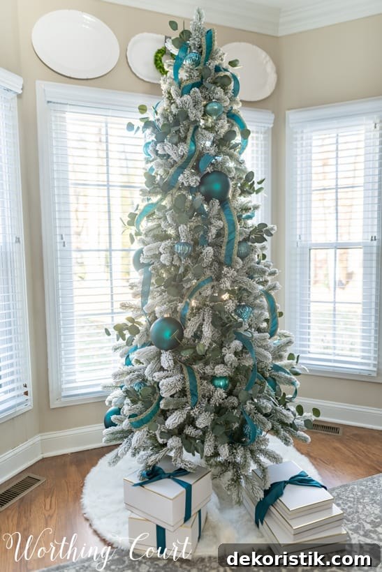 Flocked Christmas tree with teal decorations.