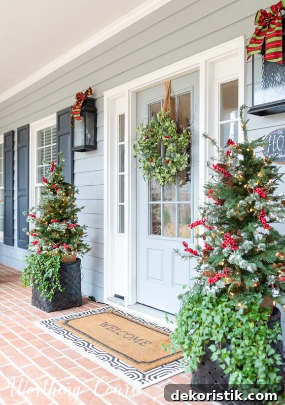 Christmas front porch decor with little Christmas trees flanking the front door.