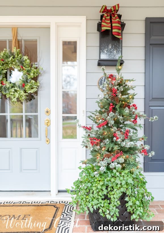 The Christmas tree has red berries on it.   There is a bow on the outdoor light.