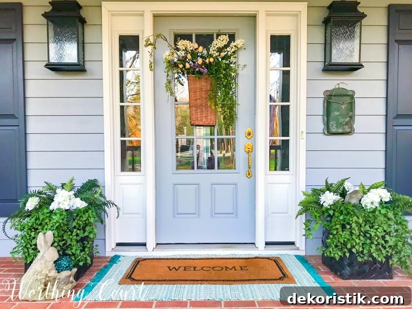 gray front door with sidelights flanked by planters and layered door mats